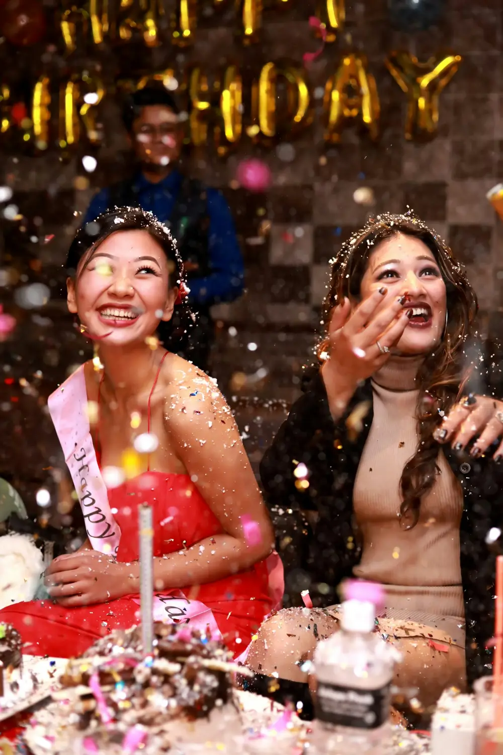 Two friends laughing as glitter falls at a party