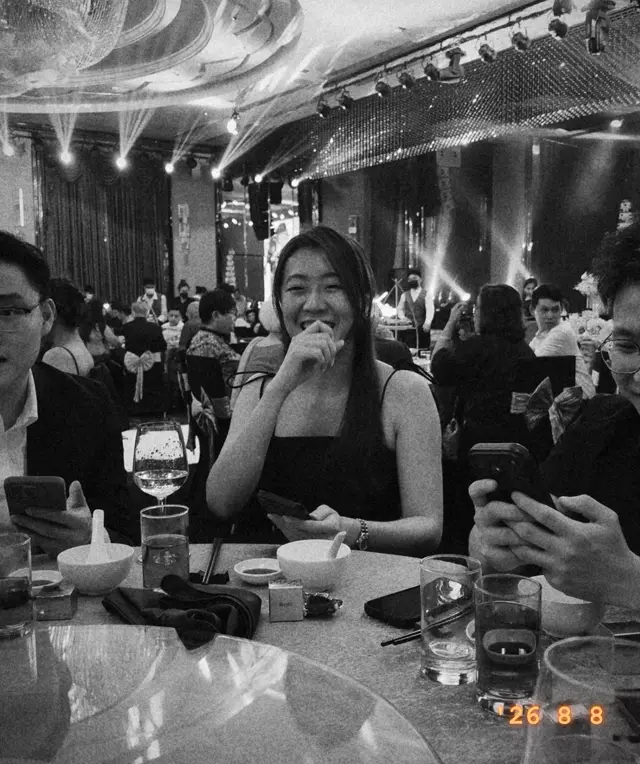 A guest smiling at her table, in black and white